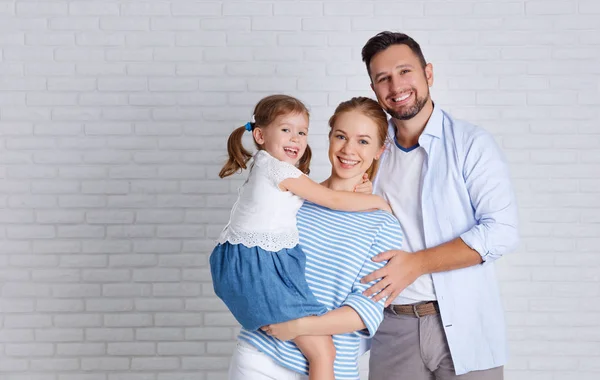 Família feliz mãe pai e filho perto de uma parede de tijolo vazio — Fotografia de Stock