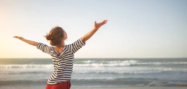 Donna felice godendo la libertà con le mani aperte sul mare — Foto Stock