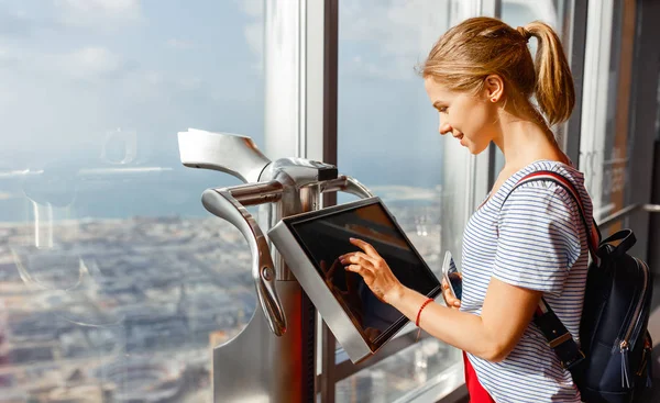 Girl tourist with monitor of computer at window of skyscraper — Stock Photo, Image