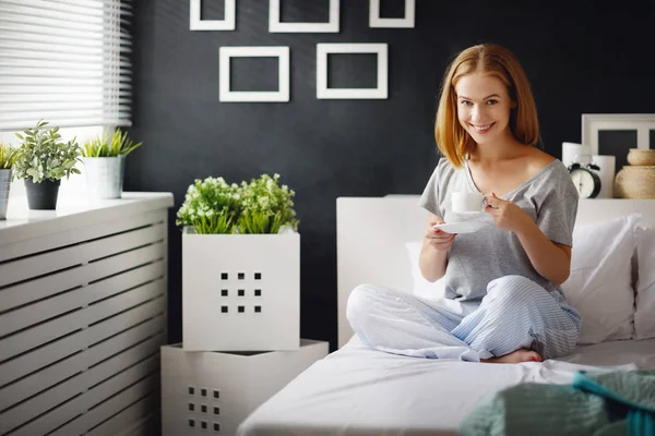 Boldog, fiatal nő, csésze reggeli kávé az ágyban — Stock Fotó