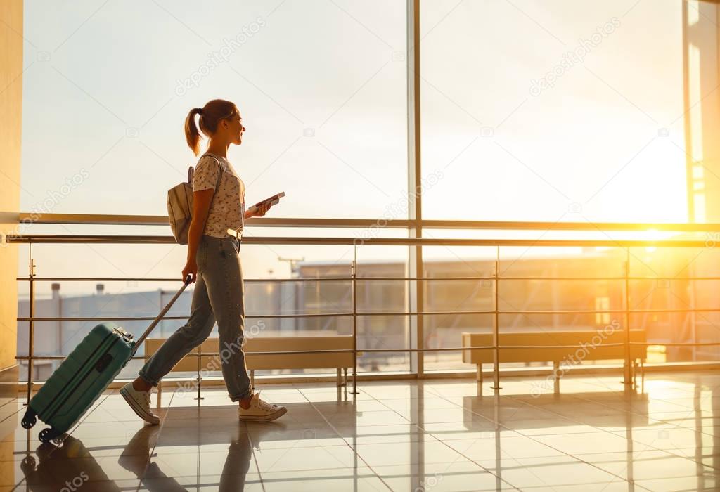 young woman goes  at airport at window with suitcase waiting for