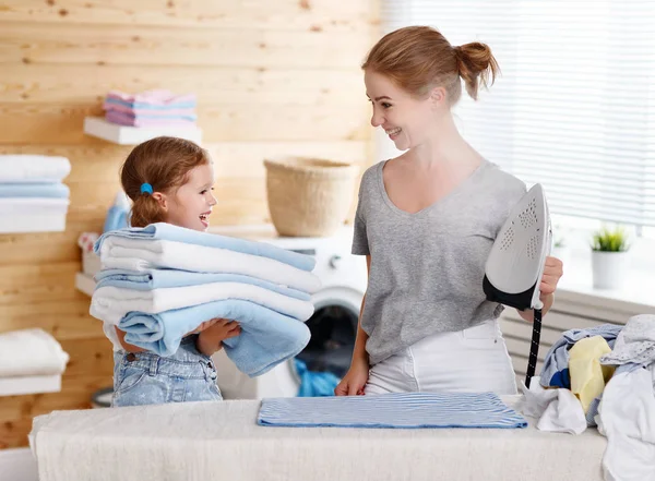 Lycklig familj mamma hemmafru och barn dotter stryka kläder — Stockfoto