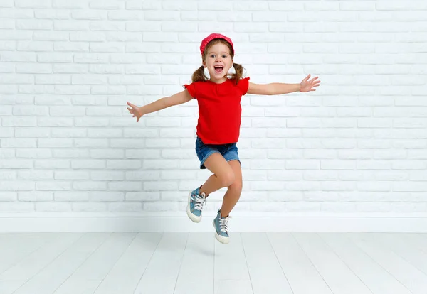 Bambino felice ragazza saltando intorno al muro vuoto — Foto Stock