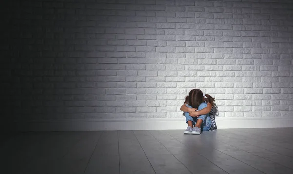 Upset sad sad child girl in stress cries at an empty dark wall — Stock Photo, Image