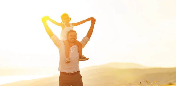 Vaderdag. kind dochter zit op de schouders van haar vader buitenshuis — Stockfoto