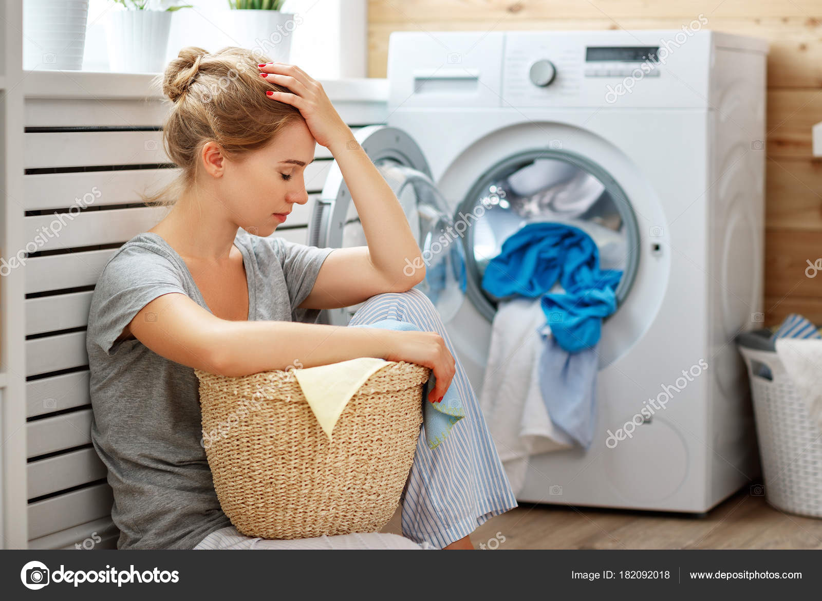 Müde Hausfrau schläft im Stress in Waschküche mit Waschmaschine