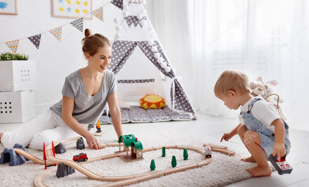 happy family mother and child son playing   in toy railway in pl