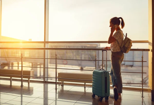 Жінка розмовляє по телефону, чекаючи літати в аеропорту у вікні — стокове фото