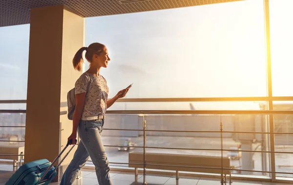 Ung kvinna går på flygplats på fönster med resväska väntar — Stockfoto