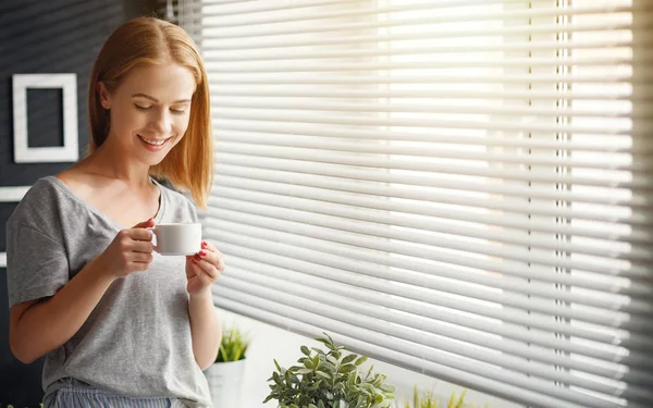 Happy young woman with cup of morning coffee in bed — Stock Photo, Image