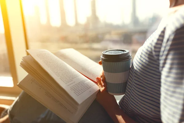 Mani di donna con caffè e un libro da finestra — Foto Stock