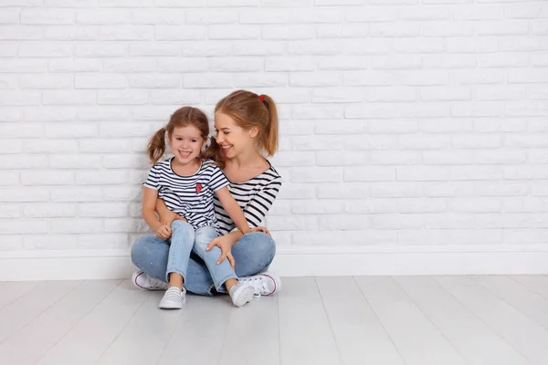 Happy family mother and child daughter near an empty wall — Stock Photo, Image