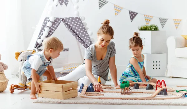 Familie moeder en kinderen spelen een smalspoorlijn van speelgoed in de speelkamer — Stockfoto