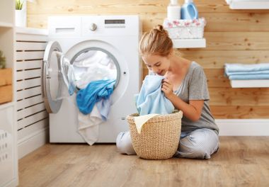 Çamaşır odasında çamaşır makinesiyle mutlu ev kadını 