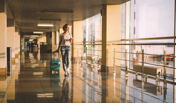 young woman goes  at airport at window with suitcase waiting for