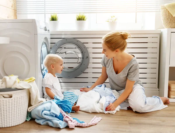 Feliz familia madre ama de casa y bebé hijo en la carga de lavandería — Foto de Stock