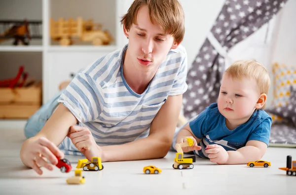 Feliz familia padre e hijo jugando en coche de juguete en la sala de juegos —  Fotos de Stock