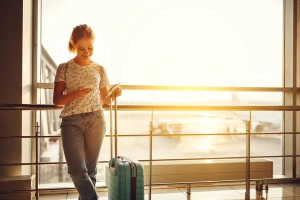 Ung kvinna väntar flyger på flygplatsen på fönster med väskorna — Stockfoto