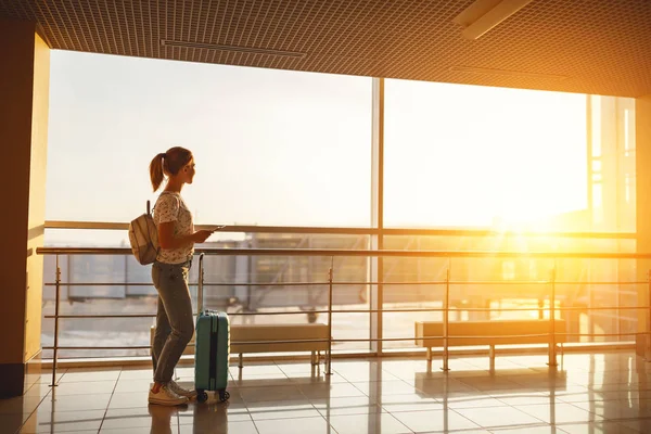 Jeune femme attendant de voler à l'aéroport à la fenêtre avec des valises — Photo
