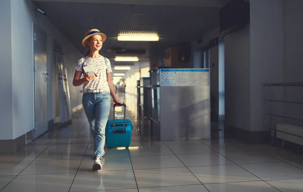 Νεαρή γυναίκα πηγαίνει στο αεροδρόμιο στο παράθυρο με βαλίτσα που περιμένει — Φωτογραφία Αρχείου