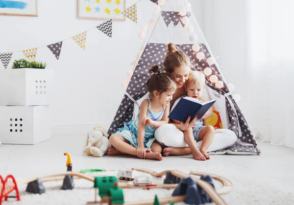 Famille mère lecture aux enfants réserver dans la tente à la maison — Photo