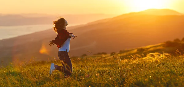 Счастливая женщина на закате на природе с распростертыми руками — стоковое фото