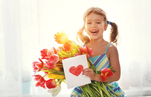 Gelukkige moederdag! meisje met briefkaart en bloemen tulpen voor mo — Stockfoto