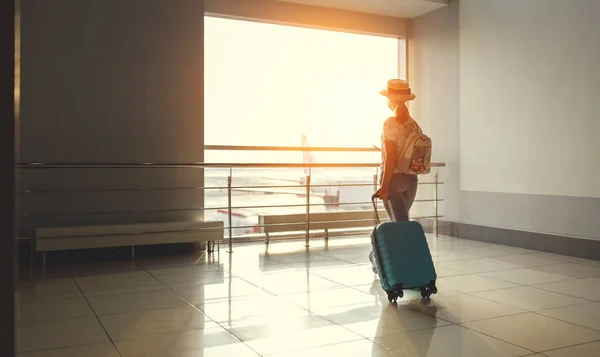 Wanita muda menunggu untuk terbang di bandara di jendela dengan koper — Stok Foto