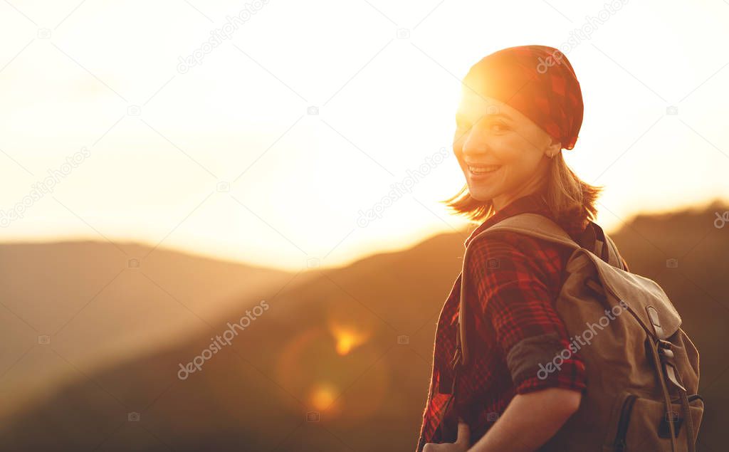 Woman tourist at top of mountain at sunset outdoors during  hike