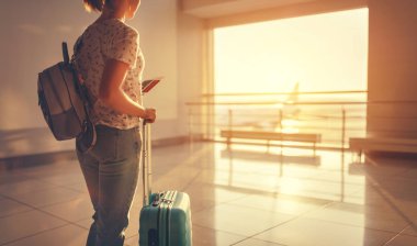 suitcas ile pencerede havaalanında uçtuğunuz için bekleyen genç kadın