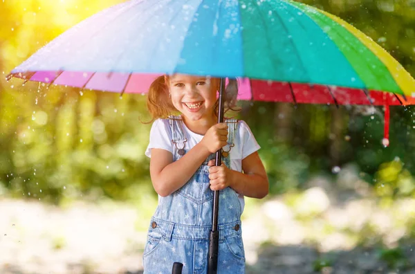 Szczęśliwe dziecko dziewczynka śmieje się i gra pod letni deszcz z zachwycającą d — Zdjęcie stockowe