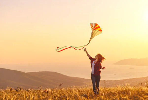 Gelukkig jonge vrouw met kite waarop glade bij zonsondergang in de zomer — Stockfoto