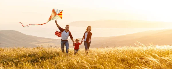 Gelukkig gezin vader, moeder en kind dochter lanceren een vlieger op — Stockfoto