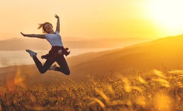 Mulher feliz pulando e aproveitando a vida ao pôr do sol na montanha — Fotografia de Stock