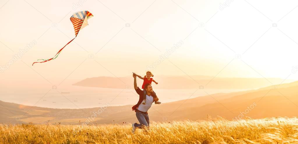 happy family father and child daughter run with  kite on meadow