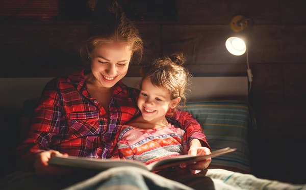 Мать и ребенок читают книгу в постели перед сном — стоковое фото