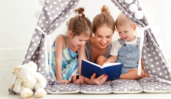 Сімейна мати читає дітям книгу в наметі вдома — стокове фото