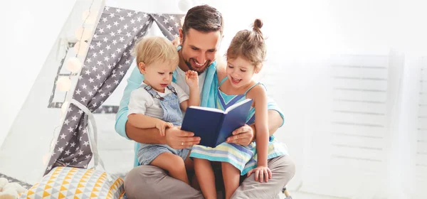 Батько сім'ї читає дітям книгу в наметі вдома — стокове фото