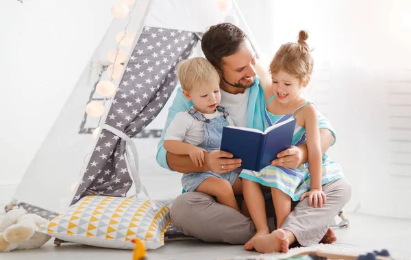 Family father reading to children book in tent at home — Stock Photo, Image