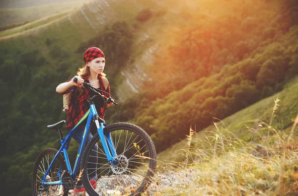 Жінка туристка на велосипеді на вершині гори на заході сонця на відкритому повітрі — стокове фото