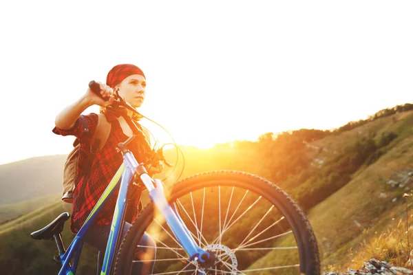 Woman tourist on a bicycle at top of mountain at sunset outdoors — Stock Photo, Image