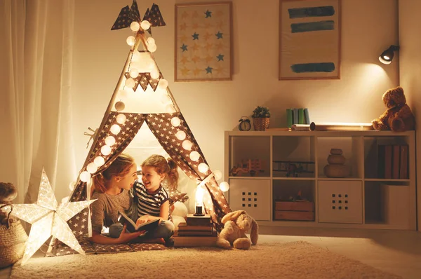 Мати і дитина дочка читають книгу і ліхтарик раніше — стокове фото