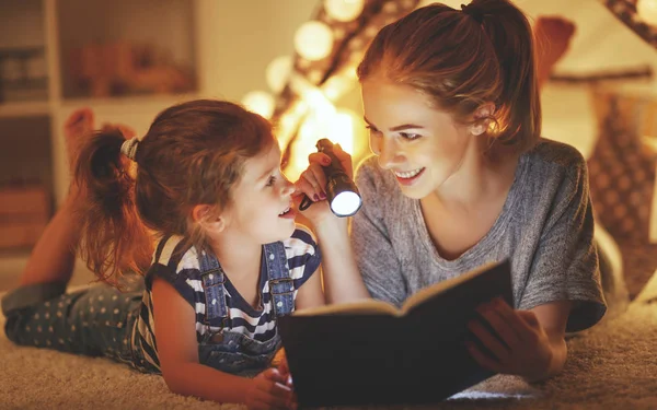 Mutter und Kind lesen vorher ein Buch und eine Taschenlampe — Stockfoto