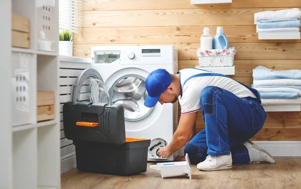 Working man   plumber repairs  washing machine in   laundr — Stock Photo, Image