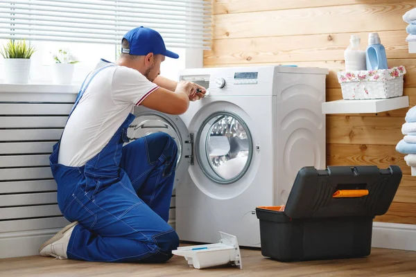 Working man   plumber repairs  washing machine in   laundr — Stock Photo, Image