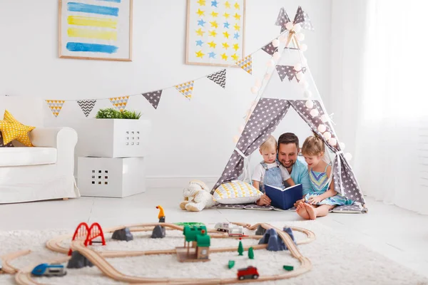 Familie vader lezen kinderen boek in tent thuis — Stockfoto