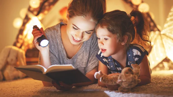 Mother and child daughter reading a book and a flashlight before — Stock Photo, Image