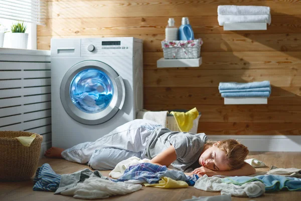 Tired housewife woman in stress sleeps in laundry room with wash — Stock Photo, Image