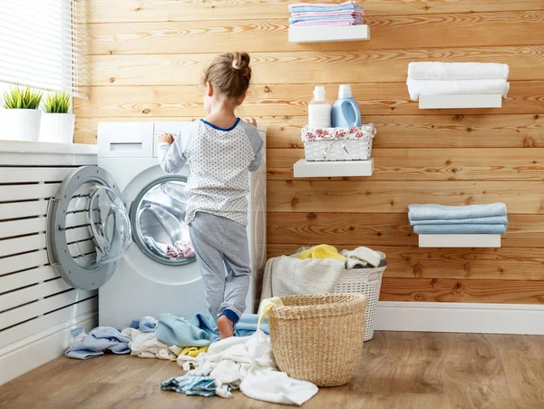 Счастливая домохозяйка ребенок девочка в прачечной со стиральной машиной — стоковое фото
