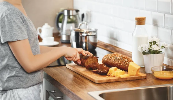 Händer kvinnor skära bröd och ost till frukost — Stockfoto
